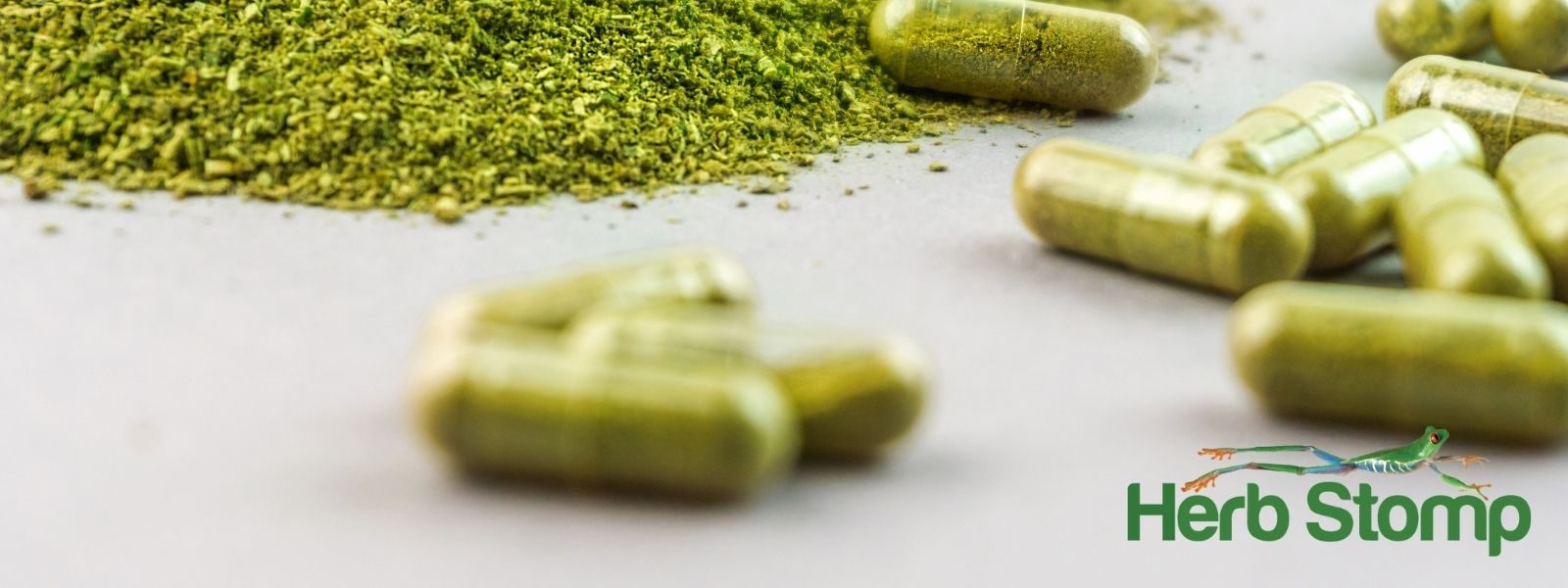 Kratom capsules next to a pile of milled kratom powder